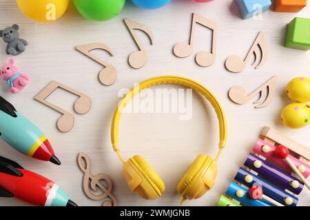 Concept de chanson de bébé. Notes en bois, écouteurs et jouets sur table, plat Banque D'Images