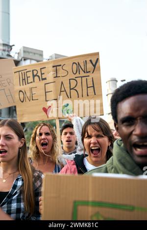 Groupe multiracial de personnes non conformes manifestation contre les usines de pollution criant furieusement. Banque D'Images