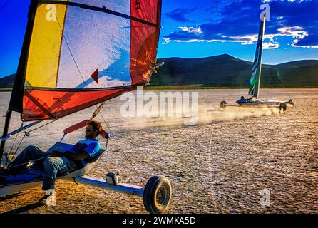 Les yachts terrestres courent le vent et les uns les autres sur le terrain plat et poussiéreux d'Alvord Desert playa. Les fans du sport affluent à l'ancien lit du lac dans s... Banque D'Images