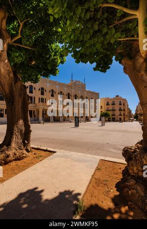 Vue à travers les arbres du bâtiment du bureau de poste dans la ville de Trapani ; Trapani, Sicile, Italie Banque D'Images