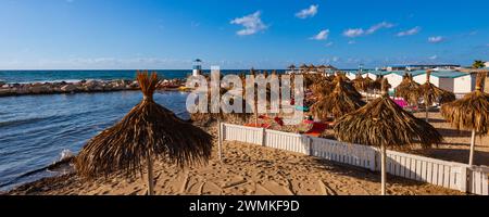 Parasols Tiki, cabanes de plage et chaises longues sur la plage du Lido Paradiso près de la ville de Trapani ; Trapani, Sicile, Italie Banque D'Images