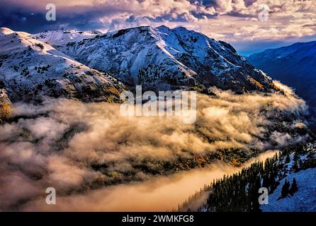 Le brouillard et les nuages bas remplissent les vallées entourant les sommets enneigés des montagnes sauvages et accidentées de San Juan. Arbres d'argent, pas la lumière du soleil, L... Banque D'Images
