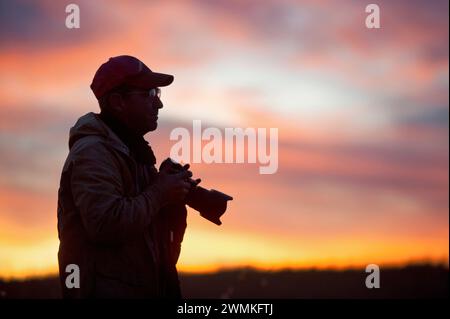 Silhouette d'un homme dehors avec une caméra au coucher du soleil ; Valentine, Nebraska, États-Unis d'Amérique Banque D'Images