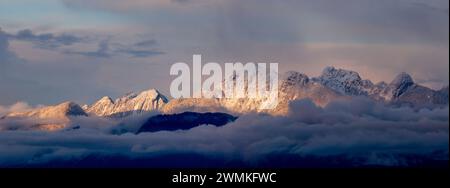 Enneigé, les sommets de montagne 'Golden Ears' de la chaîne des Garibaldi, émergent au-dessus des nuages ensoleillés avec la lueur dorée du crépuscule, une partie de la... Banque D'Images