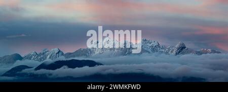 Enneigés, les sommets des montagnes des Garibaldi Ranges émergent au-dessus des nuages roses au crépuscule, faisant partie des montagnes côtières Banque D'Images