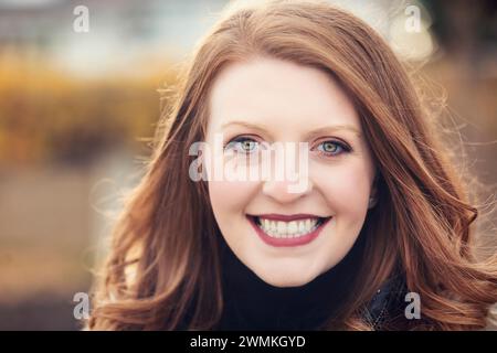 Portrait en gros plan d'une belle femme posant pour la caméra lors d'une sortie d'automne dans un parc de la ville ; Edmonton, Alberta, Canada Banque D'Images