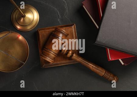 Marteau en bois, bloc sonore et livres sur table texturée sombre, pose à plat Banque D'Images