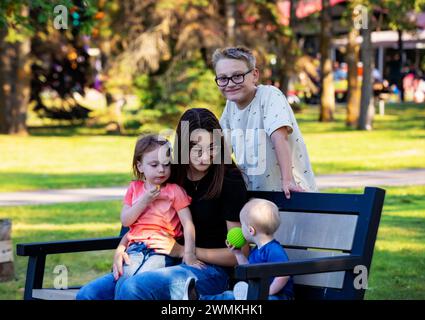 Portrait de quatre sifflements profitant de temps de qualité ensemble dans un parc de la ville, au cours d'un chaud après-midi d'automne et le plus jeune garçon a le syndrome de Down Banque D'Images