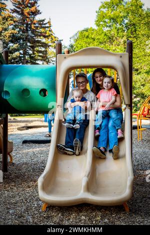 Portrait de quatre sifflements profitant de temps de qualité ensemble dans un parc de la ville, au cours d'un chaud après-midi d'automne et le plus jeune garçon a le syndrome de Down Banque D'Images