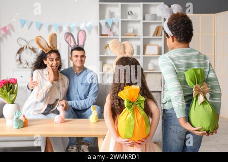 Petits enfants avec des oeufs cadeaux pour leurs parents à la maison le jour de Pâques Banque D'Images