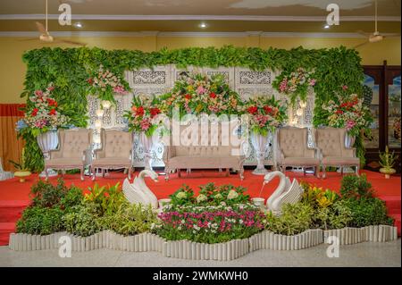 Décoration de mariage indonésienne avec un fond en bois décoré de fleurs, de lustres et de belles chaises Banque D'Images