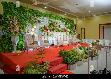 Décoration de mariage indonésienne avec un fond en bois décoré de fleurs, de lustres et de belles chaises Banque D'Images