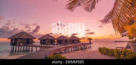 Coucher de soleil sur l'île des Maldives, luxueux complexe de villas aquatiques et jetée en bois. Magnifiques nuages de ciel et plage nature fond pour les vacances d'été Banque D'Images