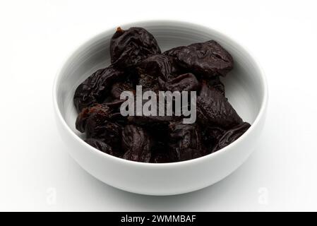 Prunes séchées dans un bol blanc isolé sur fond blanc Banque D'Images