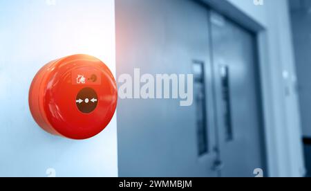 Station de poussée manuelle du système d'alarme incendie, installée sur le mur près de la porte de sortie de secours Banque D'Images