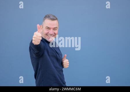 Motivation enthousiaste d'âge moyen attrayant man giving Thumbs up un geste d'approbation et le succès avec un sourire rayonnant Banque D'Images