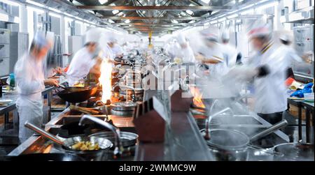 Chefs de mouvement travaillant dans la cuisine de restaurant chinois Banque D'Images