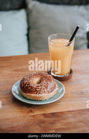 Un sandwich petit déjeuner bagel en deux avec un verre d'eau sur une table en bois Banque D'Images