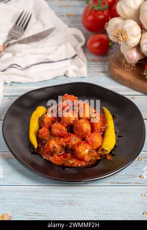 Boulettes de viande d'Alep. Hors-d'œuvre. Petites boulettes de viande avec de la pâte de tomate sur un fond en bois bleu Banque D'Images