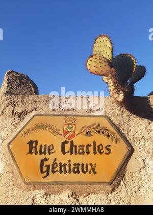 Panneau de rue typique en céramique porcelaine à Cagnes sur mer, sur un mur de pierre avec un cactus et un ciel bleu. Rue Charles Géniaux, 06800 Cagnes-sur-mer, France Banque D'Images