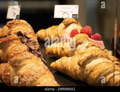 Un gros plan de croissants et de framboises exposés dans un vitrine de boulangerie Banque D'Images