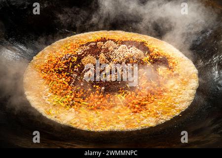 Cuisson du pilaf sur le feu dans un grand chaudron, ragoût d'agneau, de légumes, sauter des carottes et des oignons Banque D'Images