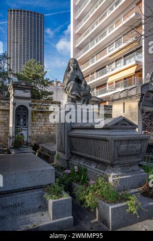 Paris, France - 02 17 2024 : cimetière de Montmartre. Vue sur une sculpture, la Tour Montparnasse et les bâtiments derrière Banque D'Images