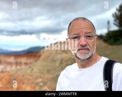homme blanc d'âge moyen avec des lunettes et t-shirt blanc regardant directement la caméra Banque D'Images