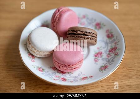 Quatre macarons délicats posés sur une assiette en porcelaine, confiserie populaire pour la texture légère, sélection de dessert petit aromatisé fruité Banque D'Images