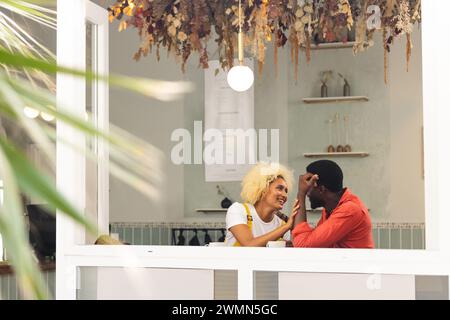 Couple biracial profite d'un moment confortable dans un café, avec espace copie Banque D'Images