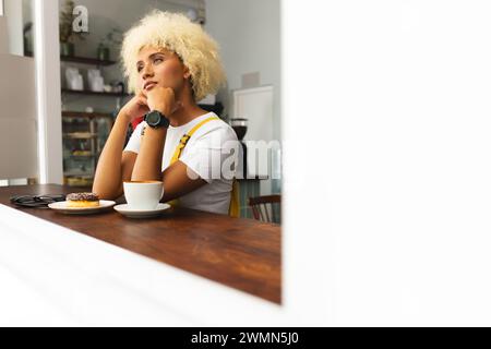 Jeune femme biraciale profite d'un moment de contemplation dans un café, avec espace copie Banque D'Images