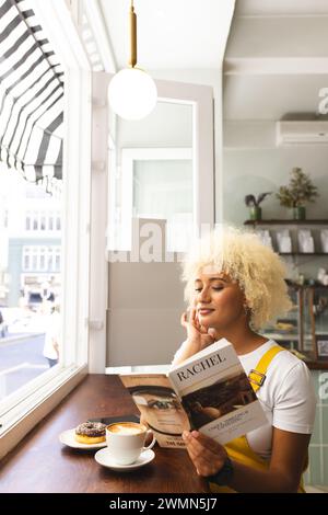 Jeune femme biraciale aime un livre dans un café confortable, avec un espace de copie Banque D'Images
