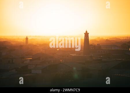 Le minaret de la mosquée sur fond de soleil orange vif pendant le coucher du soleil du soir. Banque D'Images