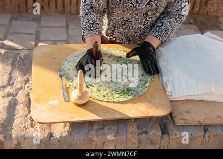 Méthode traditionnelle de cuisson du pain plat en Asie centrale Ouzbékistan, Khiva, l'oasis agricole de Khoresm, Citadelle. La femme fait du pain tandoori traditionnel Banque D'Images