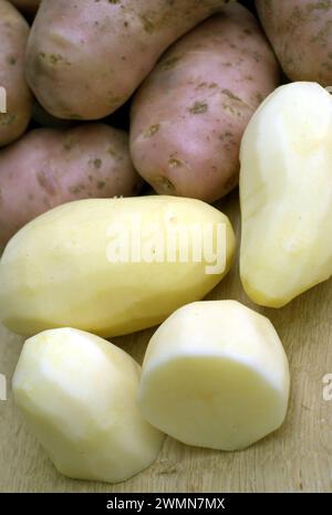 Beaucoup de pommes de terre pelées et de pommes de terre non pelées sur le bureau de cuisine dans le processus de cuisson des aliments vue rapprochée Banque D'Images