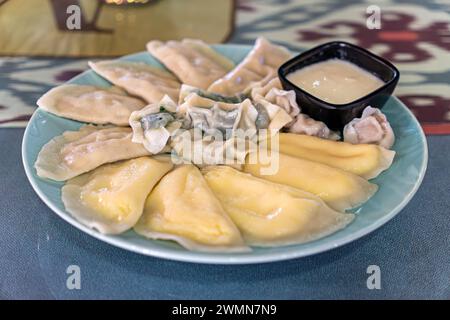 boulettes bouillies avec diverses garnitures dans une assiette avec une sauce à la crème sure sur la table dans un restaurant Banque D'Images