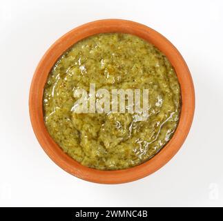 Pesto de basilic dans un bol en terre cuite sur fond blanc Banque D'Images