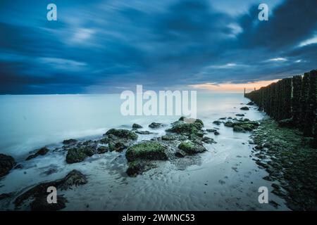 Littoral avec brise-lames et pierres de basalte pendant le temps orageux au village Westkappelle sur Walcheren dans la province de Zeeland, pays-Bas Banque D'Images