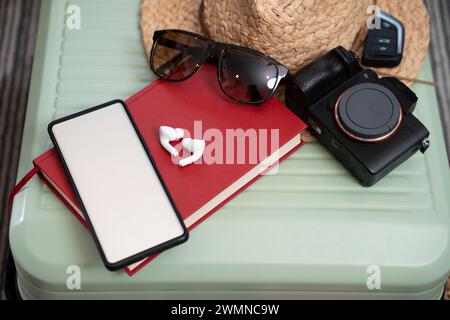 Temps de vacances, passeport, appareil photo et téléphone avec écran blanc dans la valise. Banque D'Images