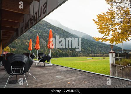 Café vide dans la vallée alpine en automne. Tables avec des parasols par temps nuageux Banque D'Images
