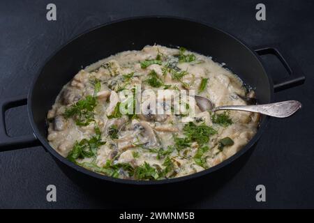 Fricassee - cuisine française. Poulet cuit dans une sauce crémeuse avec des champignons dans une poêle Banque D'Images