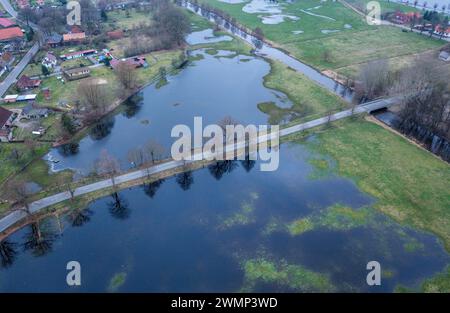 Garlitz, Allemagne. 27 février 2024. Une voiture roule sur une route de district entre deux prairies inondées après de fortes pluies. (Photo aérienne prise avec un drone) de nombreux agriculteurs du nord de l'Allemagne regardent avec une inquiétude croissante leurs champs et prairies, dont certains sont inondés ou au moins trempés. Dans une grande partie de la basse-Saxe, du Mecklembourg-Poméranie occidentale et du Schleswig-Holstein, les agriculteurs ne peuvent actuellement pas utiliser de machinerie lourde sur les sols inondés. Crédit : Jens Büttner/dpa/Alamy Live News Banque D'Images