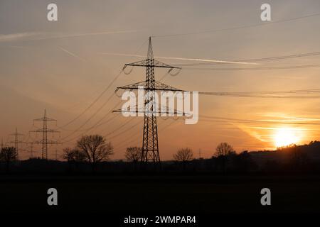 Les lignes électriques silhouettées dans la zone rurale au coucher du soleil à Giessen, Allemagne Banque D'Images