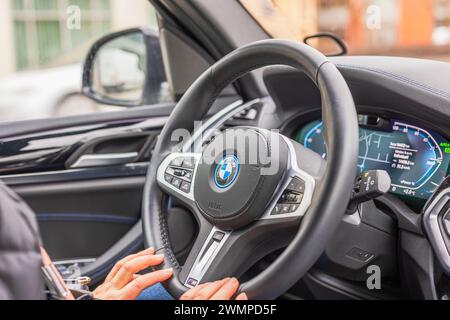 Vue rapprochée de mains féminines tenant le volant d'une voiture électrique BMW iX3-M. Suède. Uppsala. Banque D'Images