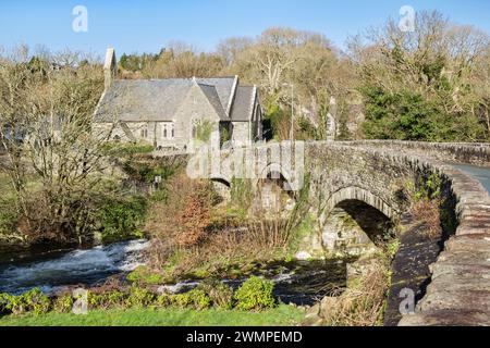 Vieux pont du XVIIIe siècle sur la rivière Afon Dwyfor avec l'église du village de St John au-delà. Llanystumdwy, Criccieth, Llyn Peninsula, Gwynedd, nord du pays de Galles Banque D'Images