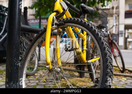 Un vélo jaune vif est garé soigneusement à côté d'un poteau noir dans un cadre urbain. Banque D'Images