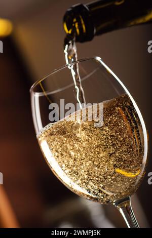 Vin blanc français se versant dans un verre en bulles avec un éclaboussure sur la table dans la cuisine, une photo studio de haute qualité, gros plan Banque D'Images