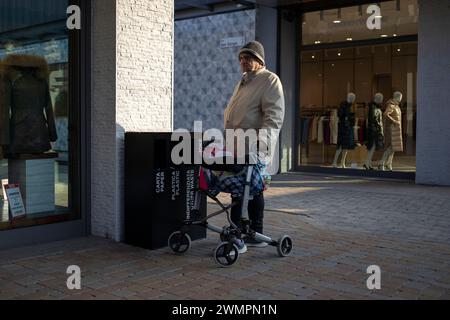 Novara, Italie, 16 janvier 2024 : un homme âgé utilisant un déambulateur à roues fait une pause dans le centre commercial Banque D'Images