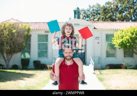 Père marchant fils à l'école. Les parents reçoivent un enfant de l'école une promenade en pigeyback. Style de vie familial. Banque D'Images