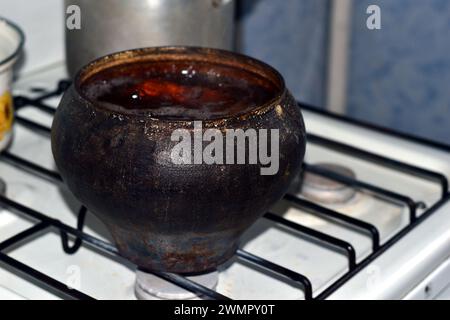 L'image montre un vieux pot en fonte sur une cuisinière à gaz, les légumes sont bouillis. Banque D'Images